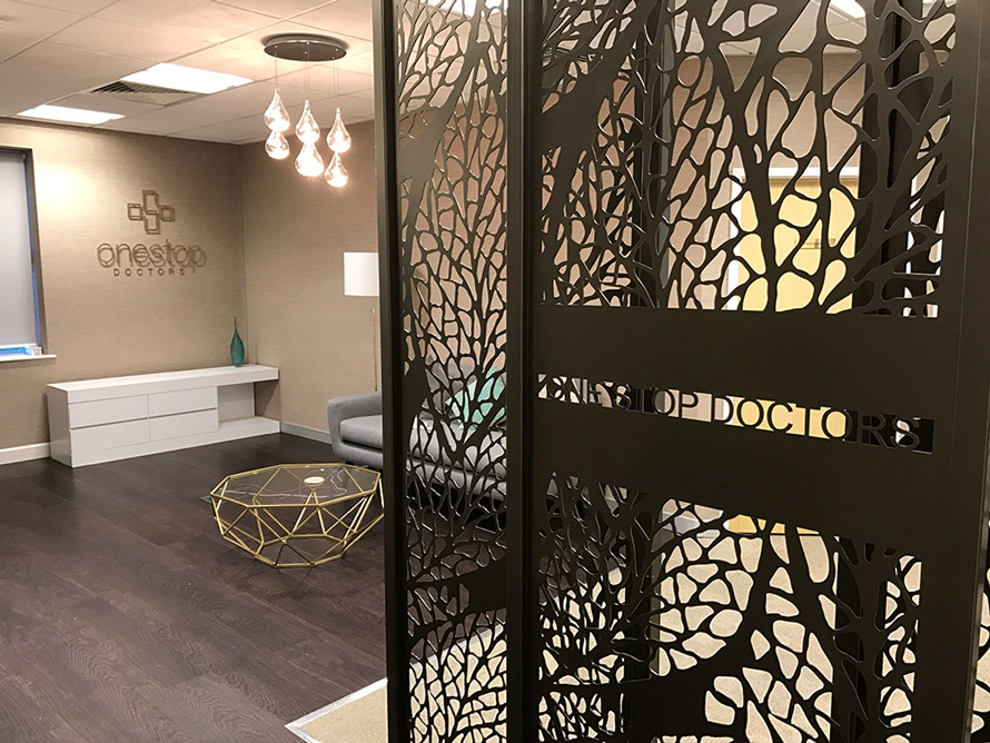 Decorative reception screens in doctors entrance hall with company logo in laser cut metal. Modern room dividers in one stop doctors logo on wall in head offiice