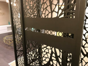 Decorative reception screens in doctors entrance hall with company logo in laser cut metal