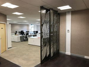 Decorative reception screens in doctors entrance hall with company logo in laser cut metal. Modern room dividers in one stop doctors head office