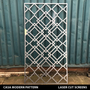 Modern geometric style laser cut fretwork with diagonal lines and squares in gold colour on a white wall